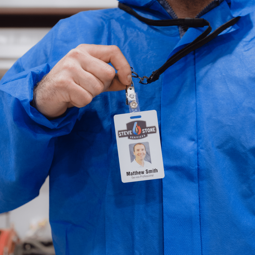 HVAC technician wearing blue protective coveralls displaying company ID badge
